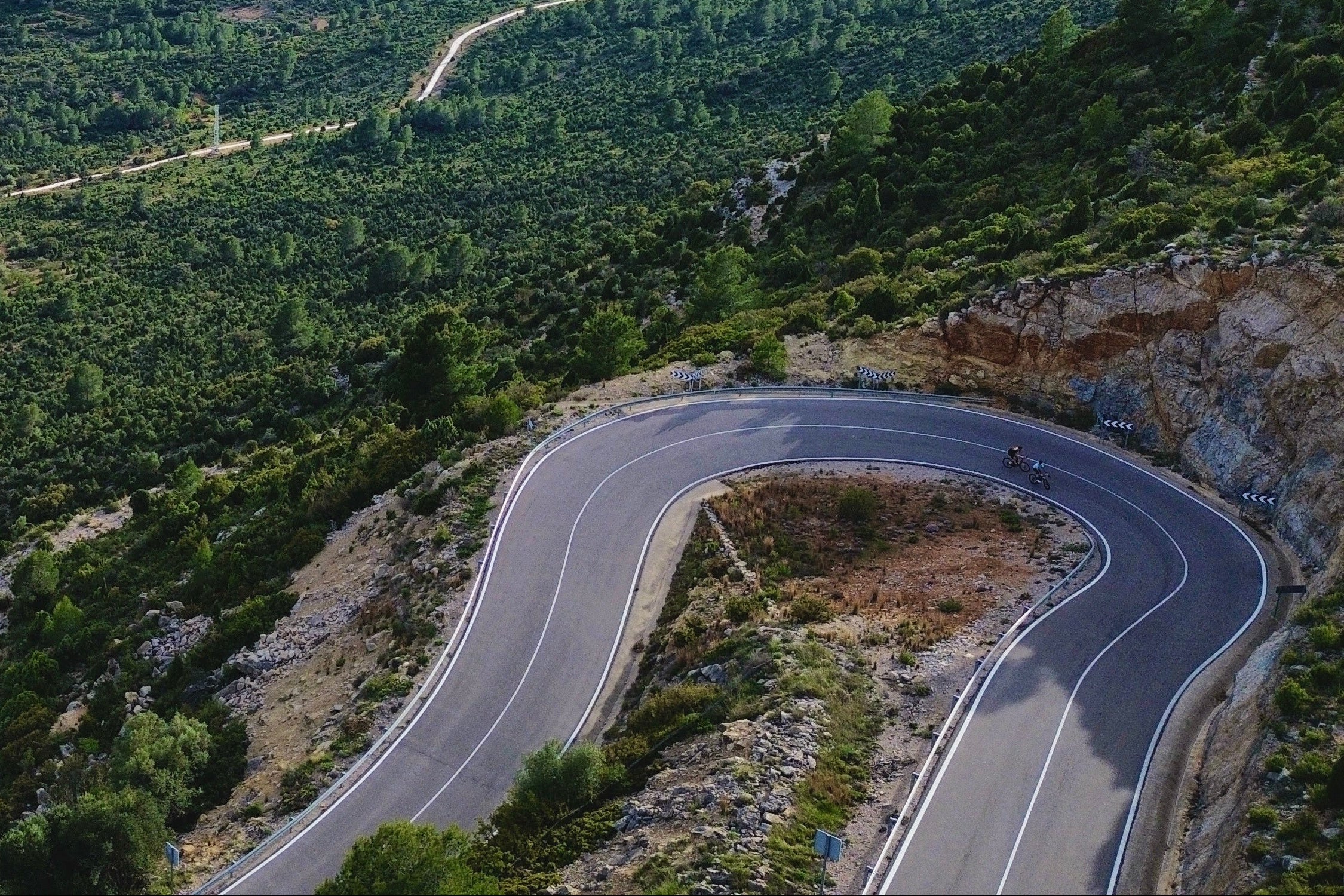 Winding road through a lush green landscape with mountains in the distance.